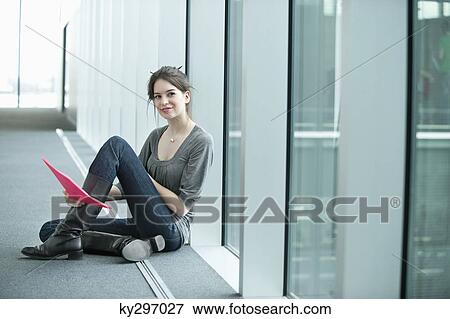 Businesswoman holding a file and sitting in an office corridor View Large Photo Image Stock Photo - Businesswoman holding a file and sitting in an office corridor. Fotosearch