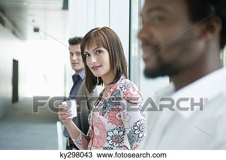 Businesswoman holding a disposable cup between her colleagues View Large Photo Image Stock Image - Businesswoman holding a disposable cup between her colleagues. Fotosearch