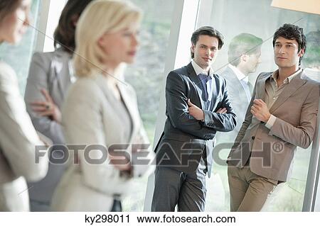 Stock Image - Two businessmen looking at their female colleagues. Fotosearch