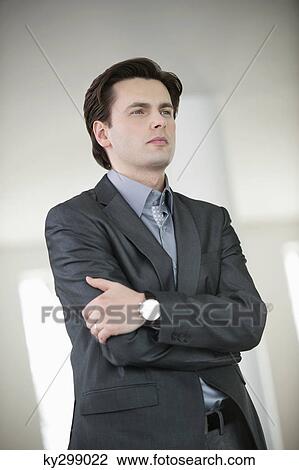 Businessman standing with his arms crossed View Large Photo Image Stock Image - Businessman standing with his arms crossed. Fotosearch