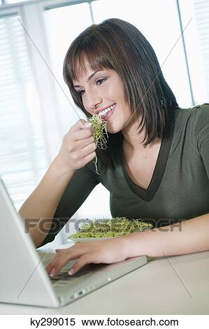 Businesswoman eating bean sprouts and using a laptop View Large Photo Image Stock Photography - Businesswoman eating bean sprouts and using a laptop. Fotosearch