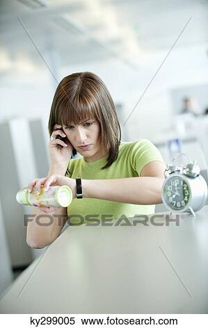 Businesswoman talking on a mobile phone and checking the time View Large Photo Image Stock Photography - Businesswoman talking on a mobile phone and checking the time. Fotosearch