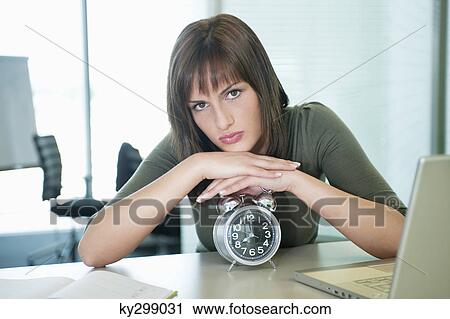 Portrait of a businesswoman leaning on an alarm clock View Large Photo Image Stock Image - Portrait of a businesswoman leaning on an alarm clock. Fotosearch