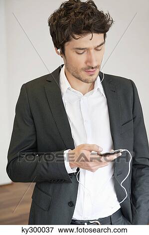 Businessman listening to music with a mobile phone View Large Photo Image Stock Photo - Businessman listening to music with a mobile phone. Fotosearch