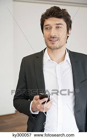 Businessman listening to music with a mobile phone View Large Photo Image Stock Photo - Businessman listening to music with a mobile phone. Fotosearch