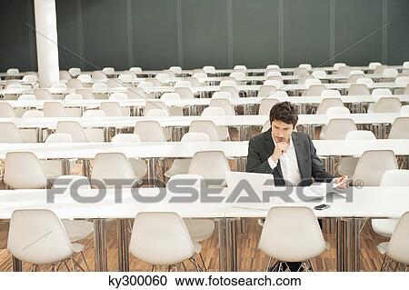 Stock Image - Businessman sitting at a cafeteria and using a laptop. Fotosearch