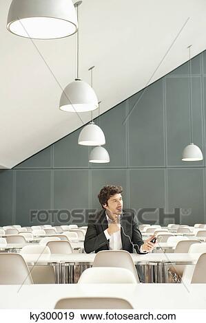 Businessman sitting at a cafeteria and talking on a mobile phone View Large Photo Image Stock Photo - Businessman sitting at a cafeteria and talking on a mobile phone. Fotosearch