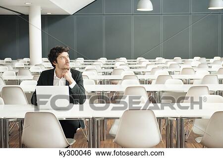 Stock Photograph - Businessman sitting at a cafeteria and using a laptop. Fotosearch
