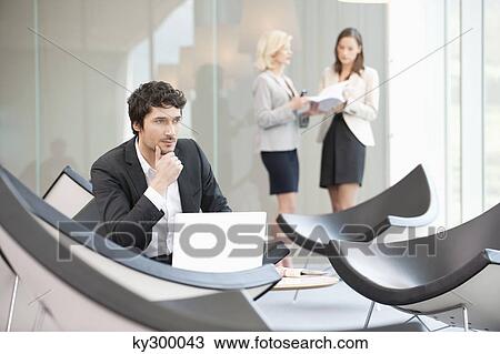 Businessman sitting in a waiting room and using a laptop View Large Photo Image Stock Image - Businessman sitting in a waiting room and using a laptop. Fotosearch