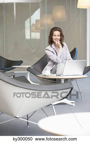 Businesswoman waiting in an office and using a laptop View Large Photo Image Stock Image - Businesswoman waiting in an office and using a laptop. Fotosearch