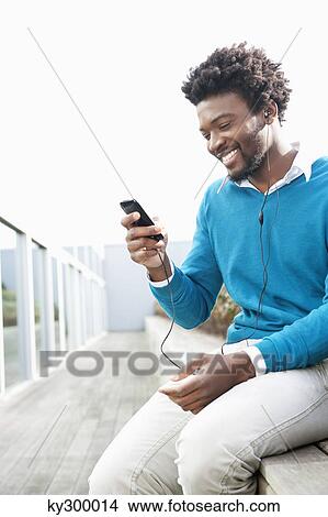 Picture - Man listening to an MP3 player. Fotosearch