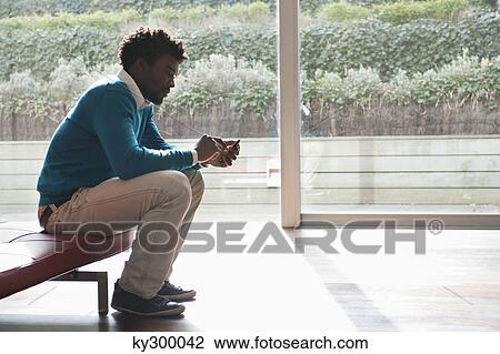 Stock Image - Man text messaging on a mobile phone. Fotosearch