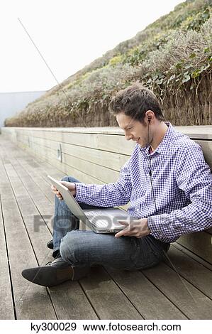 Man using a laptop and listening to music View Large Photo Image Stock Photo - Man using a laptop and listening to music. Fotosearch