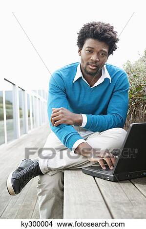 Man using a laptop on a boardwalk View Large Photo Image Picture - Man using a laptop on a boardwalk. Fotosearch