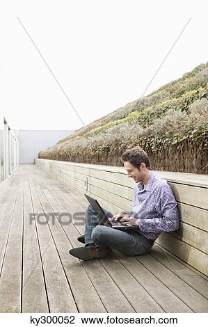 Man using a laptop on a boardwalk View Large Photo Image Stock Image - Man using a laptop on a boardwalk. Fotosearch
