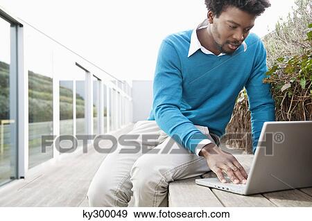 Man using a laptop on a boardwalk View Large Photo Image Stock Photo - Man using a laptop on a boardwalk. Fotosearch