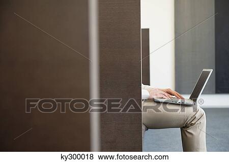 Stock Photo - Mid section view of a businessman working on a laptop in an office. Fotosearch