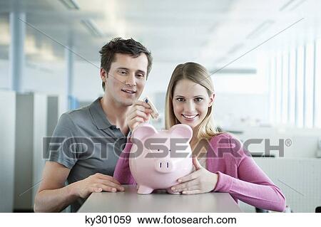 Business executives inserting a currency note into a piggy bank View Large Photo Image Stock Photo - Business executives inserting a currency note into a piggy bank. Fotosearch