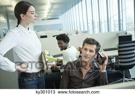 Stock Image - Businessmen listening to a radio in an office. Fotosearch