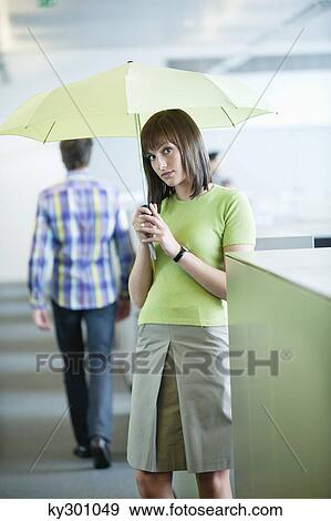 Businesswoman holding an umbrella in an office View Large Photo Image Stock Photo - Businesswoman holding an umbrella in an office. Fotosearch