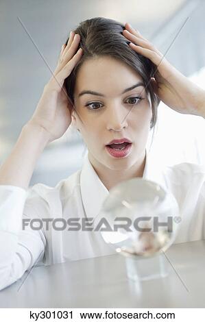 Businesswoman looking at a crystal ball and looking shocked View Large Photo Image Stock Image - Businesswoman looking at a crystal ball and looking shocked. Fotosearch