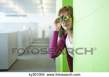 Businesswoman looking through binoculars in an office corridor View Large Photo Image Picture - Businesswoman looking through binoculars in an office corridor. Fotosearch