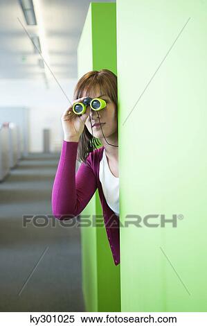 Businesswoman looking through binoculars in an office corridor View Large Photo Image Stock Photography - Businesswoman looking through binoculars in an office corridor. Fotosearch
