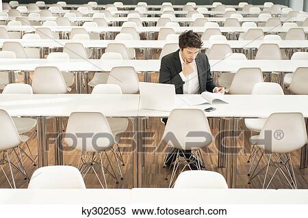 Businessman sitting at a cafeteria and reading a book View Large Photo Image Stock Image - Businessman sitting at a cafeteria and reading a book. Fotosearch
