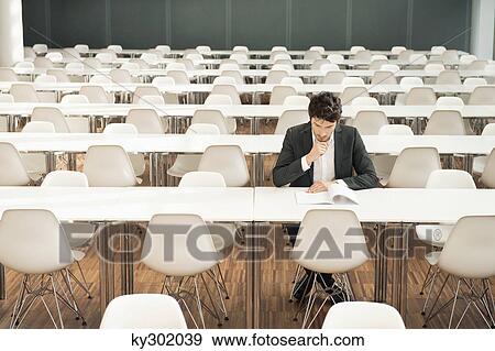 Businessman sitting at a cafeteria and reading a book View Large Photo Image Stock Photo - Businessman sitting at a cafeteria and reading a book. Fotosearch