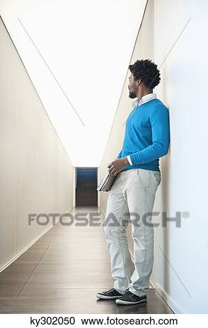 Businessman standing in the corridor of an office View Large Photo Image Stock Image - Businessman standing in the corridor of an office. Fotosearch