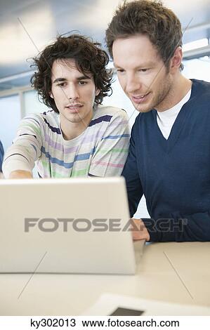 Businessmen using a laptop in an office View Large Photo Image Stock Image - Businessmen using a laptop in an office. Fotosearch