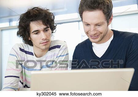 Stock Photography - Businessmen using a laptop in an office. Fotosearch