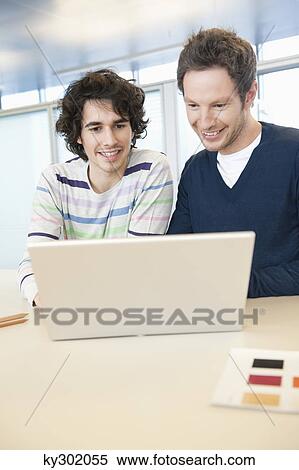 Stock Photography - Businessmen using a laptop in an office. Fotosearch