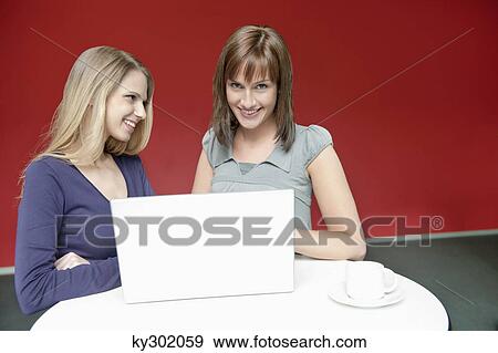 Two businesswomen using a laptop in an office View Large Photo Image Stock Photo - Two businesswomen using a laptop in an office. Fotosearch