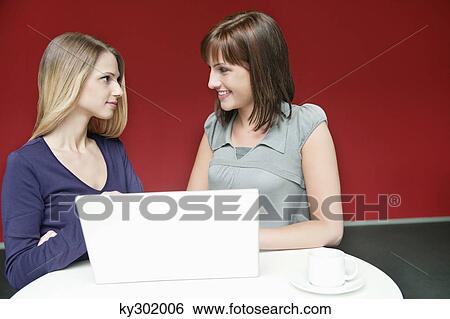 Two businesswomen using a laptop in an office View Large Photo Image Stock Photograph - Two businesswomen using a laptop in an office. Fotosearch