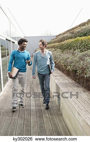 stock images of two friends walking together on a boardwalk ky302026