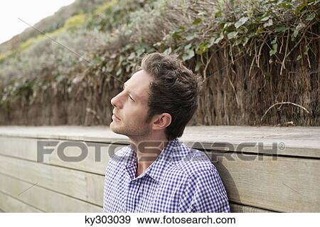 Stock Photo - Man day dreaming on a boardwalk. Fotosearch
