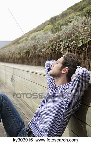Man resting on a boardwalk View Large Photo Image Stock Photograph - Man resting on a boardwalk. Fotosearch