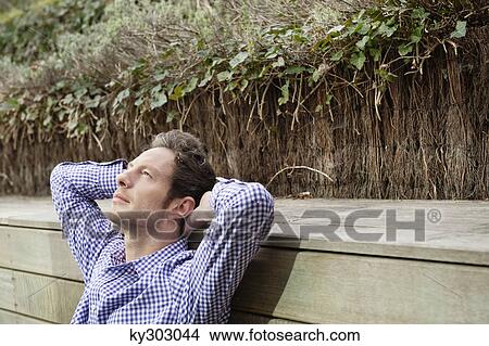 Man sitting on a boardwalk and day dreaming View Large Photo Image Picture - Man sitting on a boardwalk and day dreaming. Fotosearch