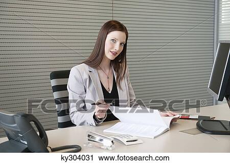 Businesswoman doing paperwork in an office View Large Photo Image Stock Image - Businesswoman doing paperwork in an office. Fotosearch