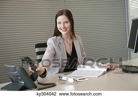 Businesswoman holding a telephone receiver in an office View Large Photo Image Stock Image - Businesswoman holding a telephone receiver in an office. Fotosearch