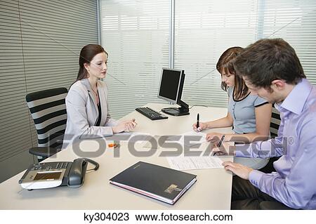 Couple signing agreement form in a real estate agent's office View Large Photo Image Stock Image - Couple signing agreement form in a real estate agent's office. Fotosearch