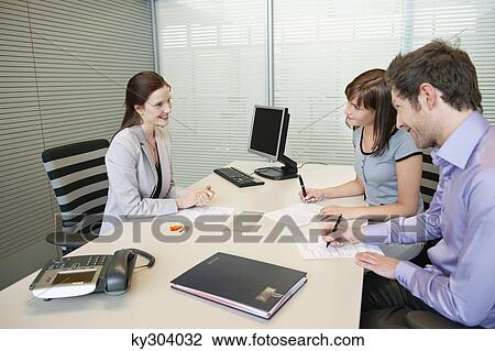 Couple signing agreement form in a real estate agent's office View Large Photo Image Stock Image - Couple signing agreement form in a real estate agent's office. Fotosearch