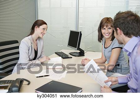 Female real estate agent and a couple discussing in an office View Large Photo Image Stock Image - Female real estate agent and a couple discussing in an office. Fotosearch