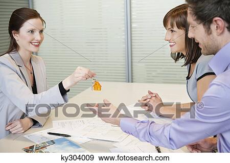 Female real estate agent giving house keys to a couple View Large Photo Image Stock Photo - Female real estate agent giving house keys to a couple. Fotosearch