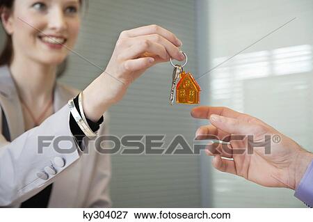 Stock Photo - Female real estate agent giving house keys to a man. Fotosearch