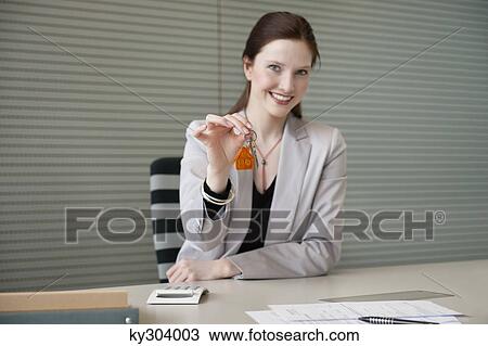 Female real estate agent holding house keys in an office View Large Photo Image Stock Image - Female real estate agent holding house keys in an office. Fotosearch