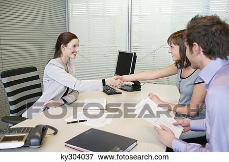 Female real estate agent shaking hands with a couple View Large Photo Image Stock Photo - Female real estate agent shaking hands with a couple. Fotosearch