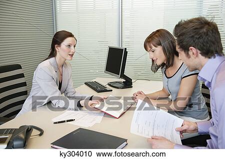 Female real estate agent showing a book to a couple View Large Photo Image Stock Image - Female real estate agent showing a book to a couple. Fotosearch