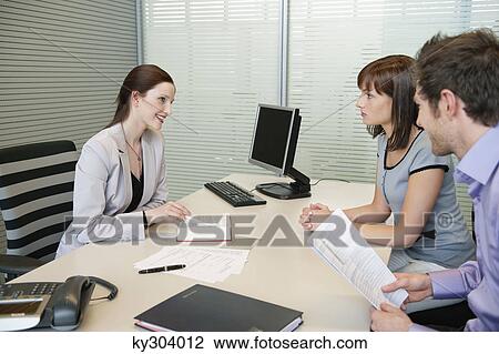 Female real estate agent showing a book to a couple View Large Photo Image Stock Image - Female real estate agent showing a book to a couple. Fotosearch